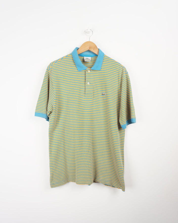 Vintage Lacoste blue and yellow striped polo shirt with embroidered logo. good condition- small hole under one armpit Size in Label: S Our Measurements: Chest: 20 inchesLength:  28 inches Please ensure you check all measurements. ** All our items are pre-loved and as a result may show signs of wear due to the age of the product, for any questions about this or any other item please email hello@vintage-folk.com **