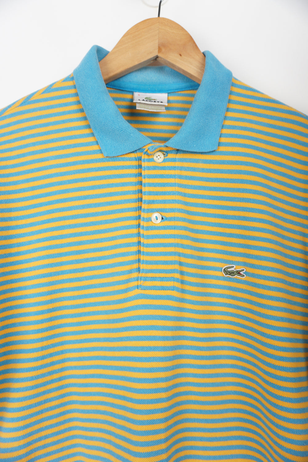 Vintage Lacoste blue and yellow striped polo shirt with embroidered logo. good condition- small hole under one armpit Size in Label: S Our Measurements: Chest: 20 inchesLength:  28 inches Please ensure you check all measurements. ** All our items are pre-loved and as a result may show signs of wear due to the age of the product, for any questions about this or any other item please email hello@vintage-folk.com **