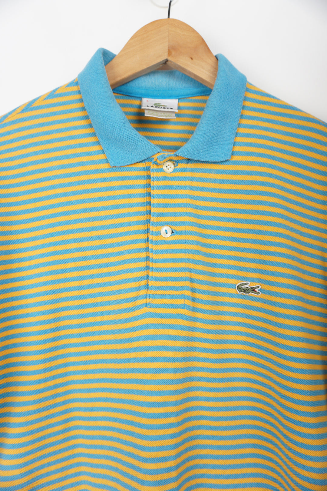Vintage Lacoste blue and yellow striped polo shirt with embroidered logo. good condition- small hole under one armpit Size in Label: S Our Measurements: Chest: 20 inchesLength:  28 inches Please ensure you check all measurements. ** All our items are pre-loved and as a result may show signs of wear due to the age of the product, for any questions about this or any other item please email hello@vintage-folk.com **