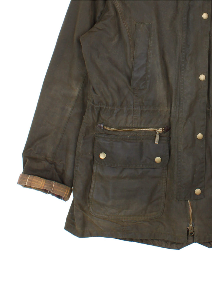 Barbour Kelsall Wax Parka Coat in a green colourway, zips and buttons up, has multiple pockets, hooded with a faux fur and sherpa lining, insulated with a quilted lining, and has the logo embroidered on the front.