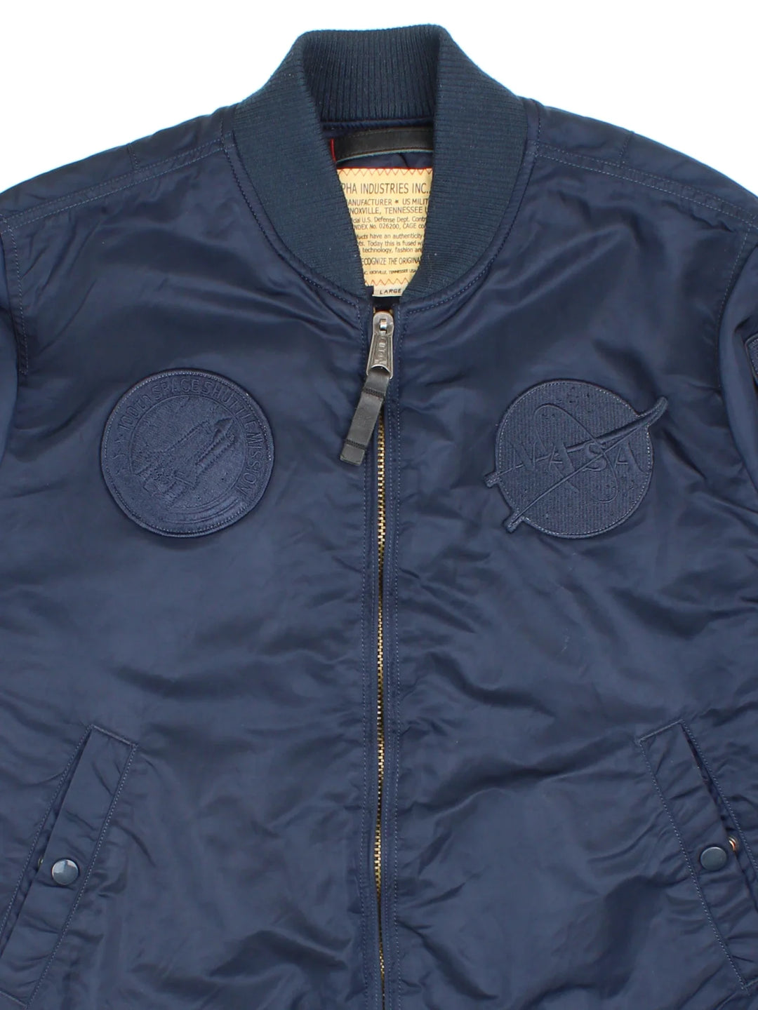 Alpha Industries NASA Bomber Jacket in a blue colourway. Zips up and has multiple pockets, insulated lining, and has the logo embroidered on the front and left sleeve.