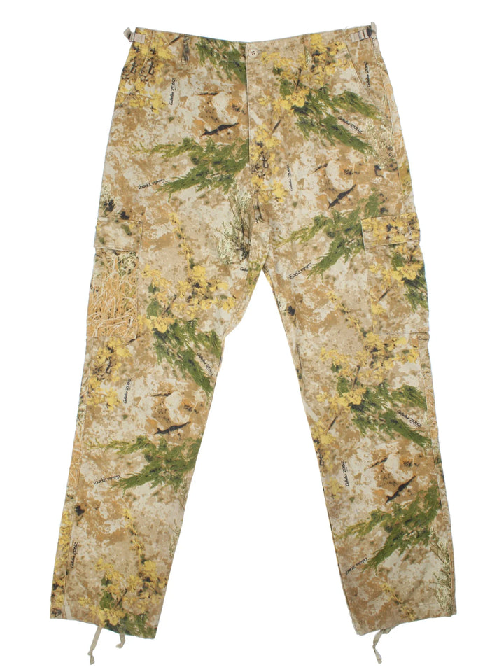 Vintage Cabelas Outdoor Camo Cargo Trousers in tan brown, and green patterned colourway with multiple pockets and the logo embroidered on the back.