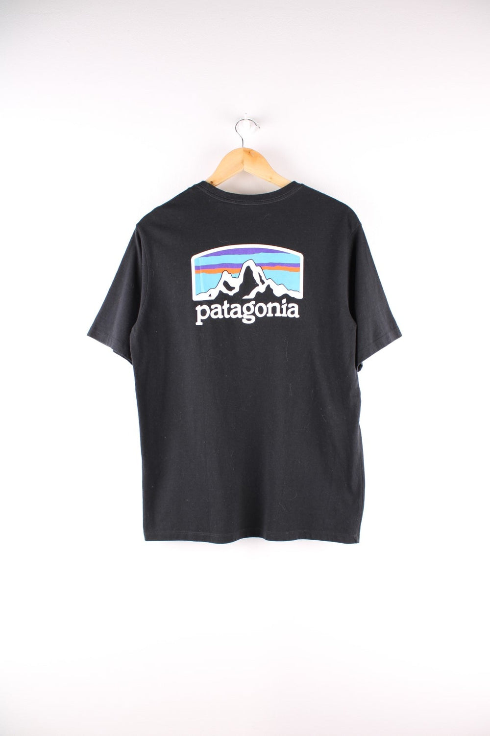 Patagonia t-shirt in black with a small spellout in white on the front, and a logo graphic on the back.