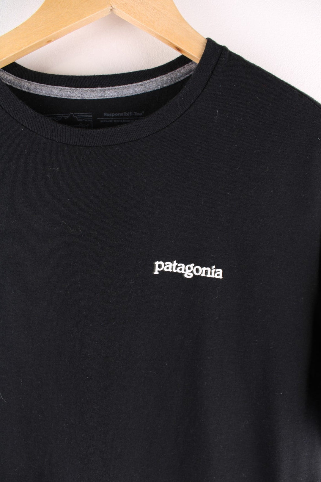 Patagonia t-shirt in black with a small spellout in white on the front, and a logo graphic on the back.