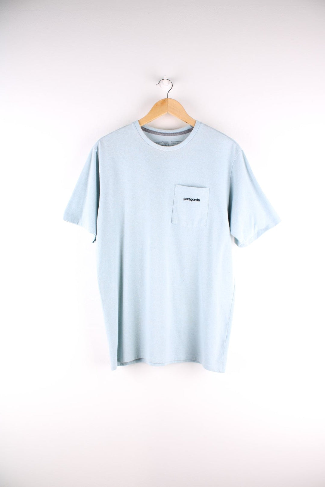 Patagonia t-shirt in blue with a chest pocket and small spellout printed on the front and large mountain logo on the back.
