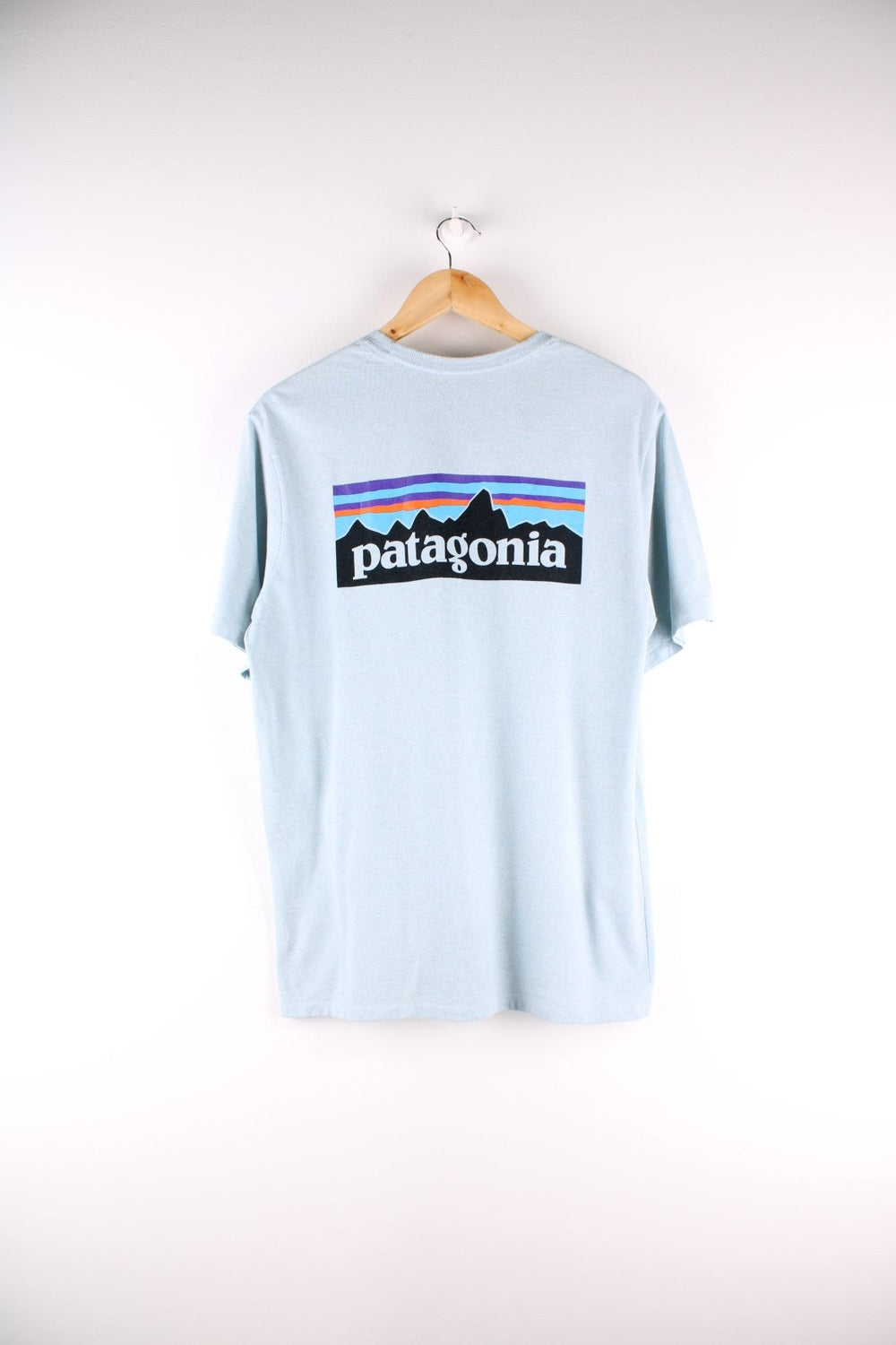 Patagonia t-shirt in blue with a chest pocket and small spellout printed on the front and large mountain logo on the back.