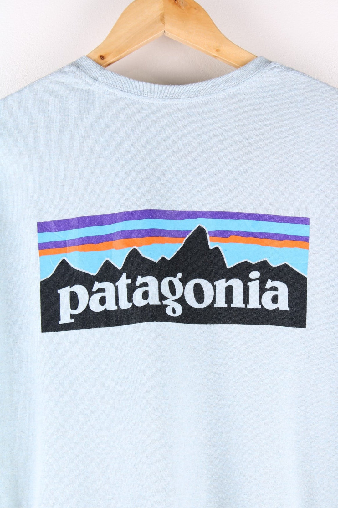 Patagonia t-shirt in blue with a chest pocket and small spellout printed on the front and large mountain logo on the back.