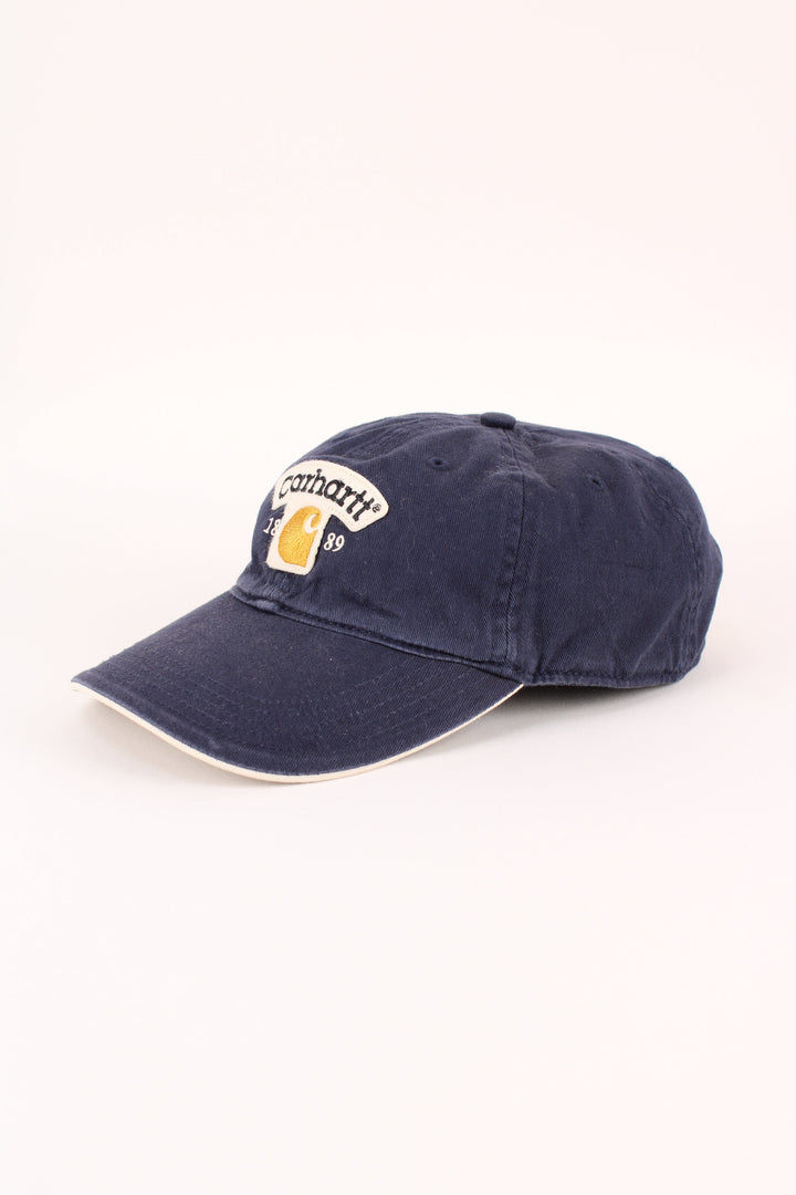 Carhartt 1989 Cap in a blue colourway with the logo embroidered on the front, and has adjustable velcro strap at the back.
