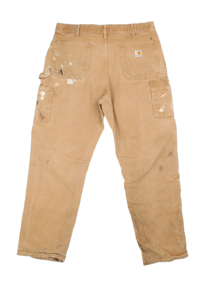 Carhartt Double Knee Jeans in a tan colourway with multiple pockets and the logo embroidered on the back.