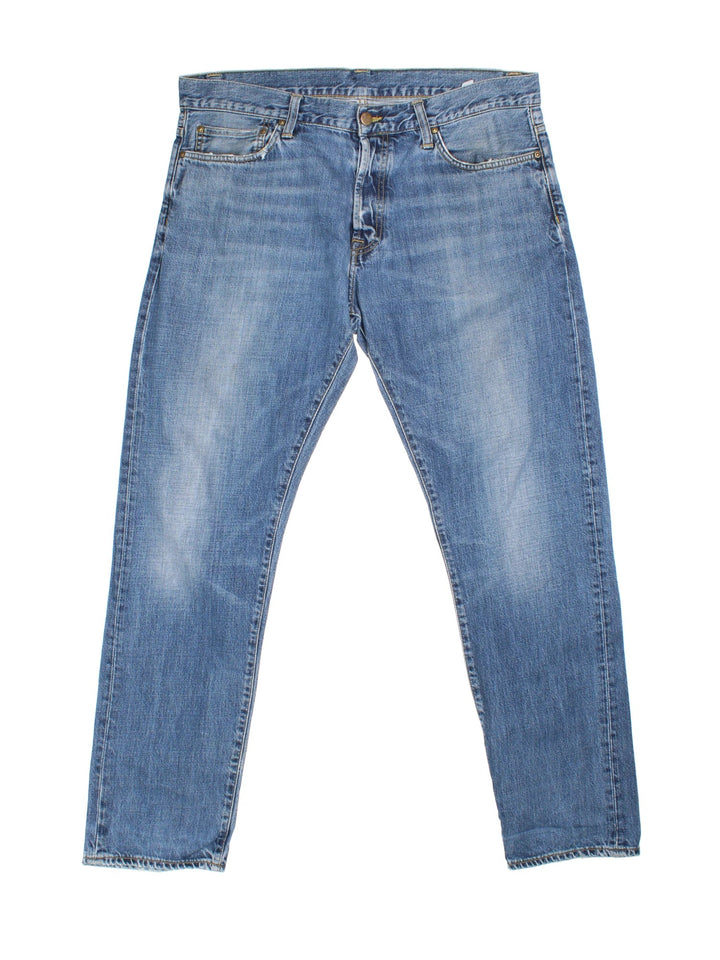 Carhartt Jeans in a blue colourway with multiple pockets and the logo embroidered on the back.