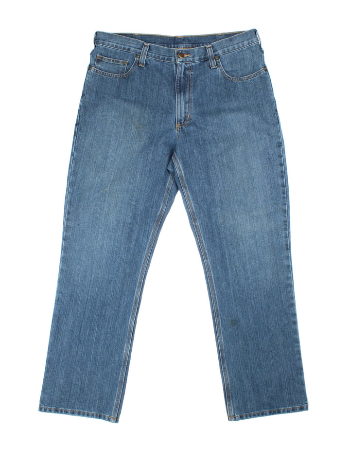 Carhartt Jeans in a blue colourway with multiple pockets, plaid pattern lining, and the logo embroidered on the back.