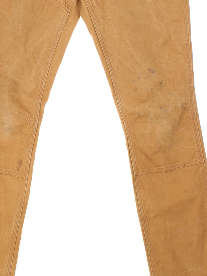 Carhartt Double Knee Jeans in a tan colourway with multiple pockets and the logo embroidered on the back.