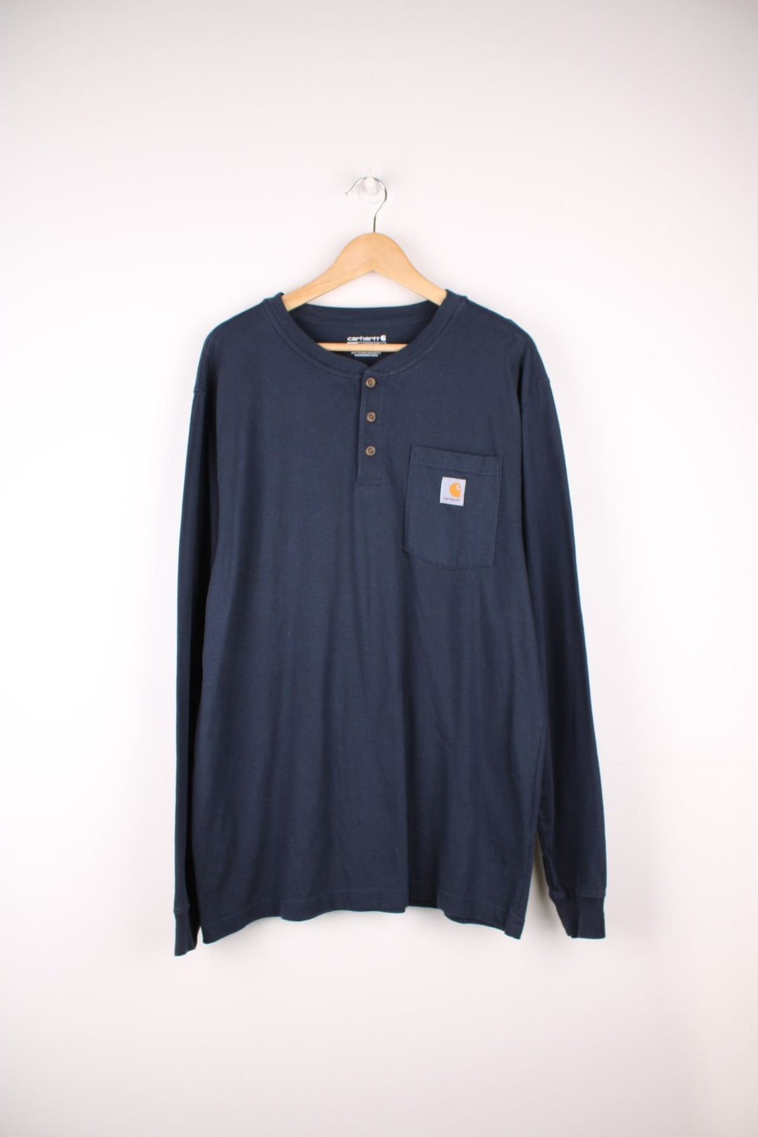 Carhartt navy blue long sleeve cotton t-shirt. Features three button fastening and signature logo on the chest pocket 