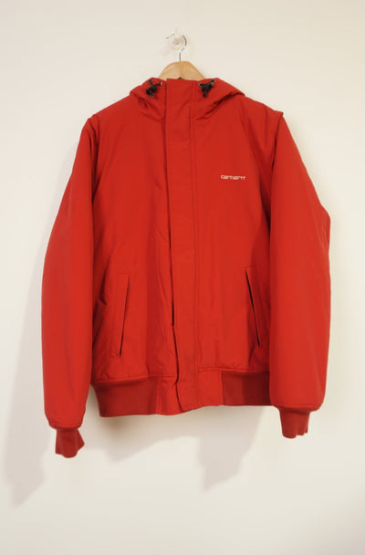 Red Carhartt outdoor coat with zip up pockets and embroidered logo on the chest