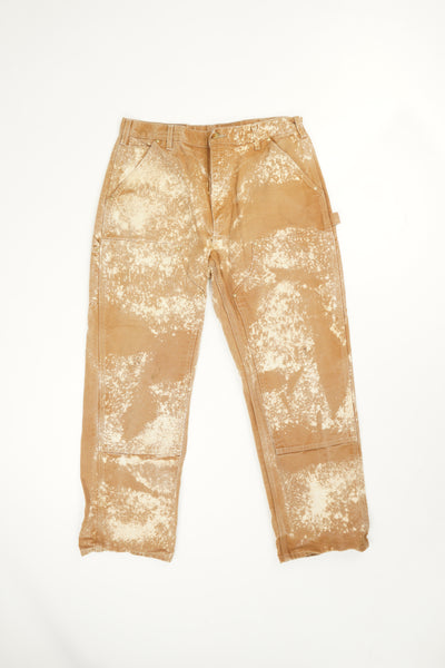 Tan Carhartt double knee carpenter style jeans with multiple pockets and bleach stain details