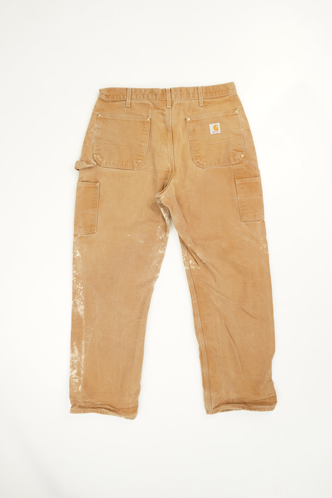 Tan Carhartt double knee carpenter style jeans with multiple pockets and bleach stain details