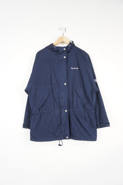 Reebok navy blue zip through windbreaker jacket features embroidered logo on the chest and reflective ribbon on the sleeves and back 