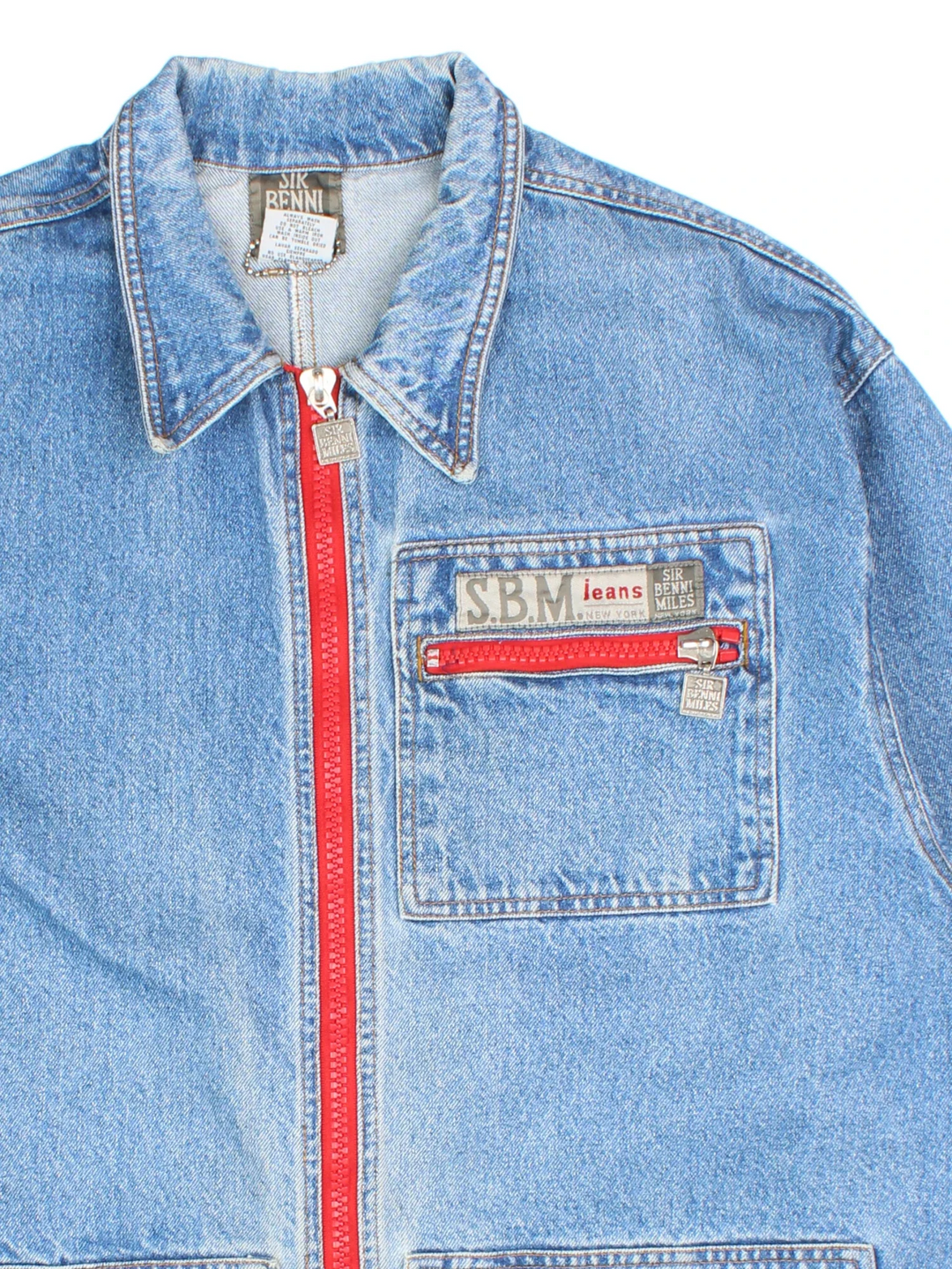 Vintage Sir Benni Miles Denim Jacket in a blue colourway with red detailing. Buttons up and has multiple pockets, and the logo embroidered on the front and back.