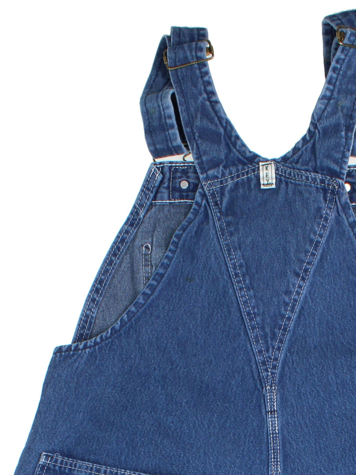 Vintage Key Imperial Dungarees in blue colourway with multiple pockets, adjustable straps, and has the logo embroidered on the front.
