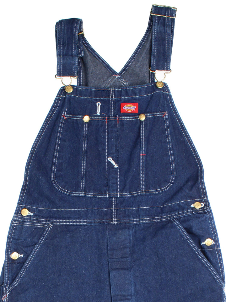 Dickies Dungarees in blue colourway with multiple pockets, adjustable straps, and has the logo embroidered on the front.