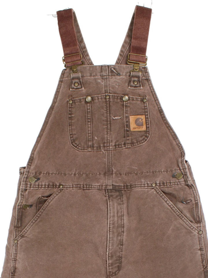 Carhartt Dungarees in brown colourway with multiple pockets, adjustable straps and the logo embroidered on the front.