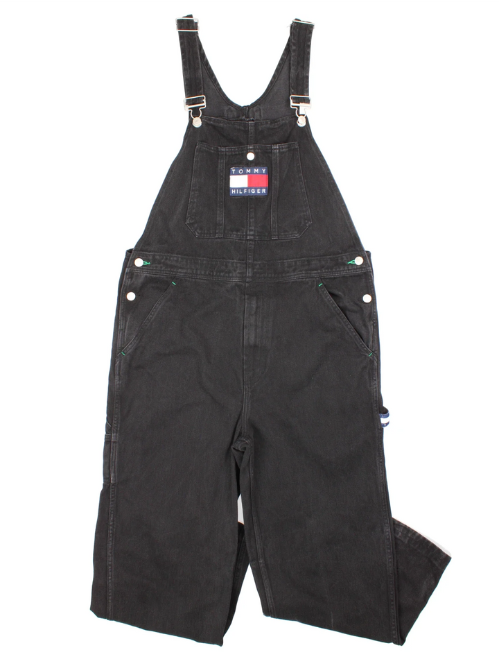 Tommy Hilfiger Dungarees in black colourway with multiple pockets, branded buttons and the logo embroidered on the front/back.