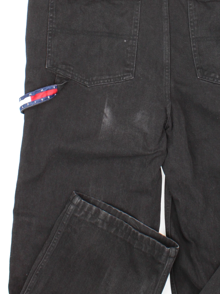 Tommy Hilfiger Dungarees in black colourway with multiple pockets, branded buttons and the logo embroidered on the front/back.