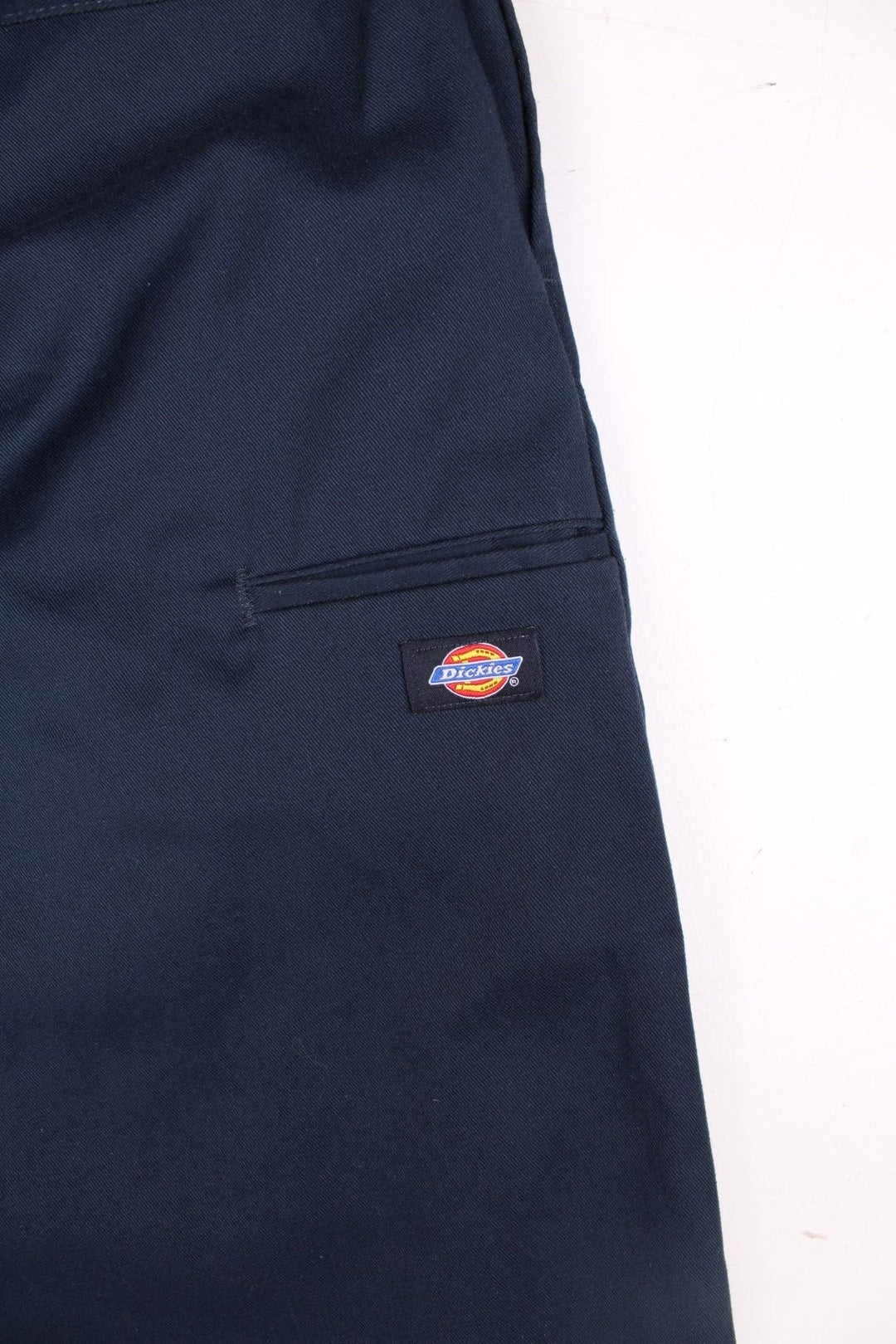 Dickies double-knee work trousers in navy blue with multiple pockets, zip and button closure, and a logo patch on the front.