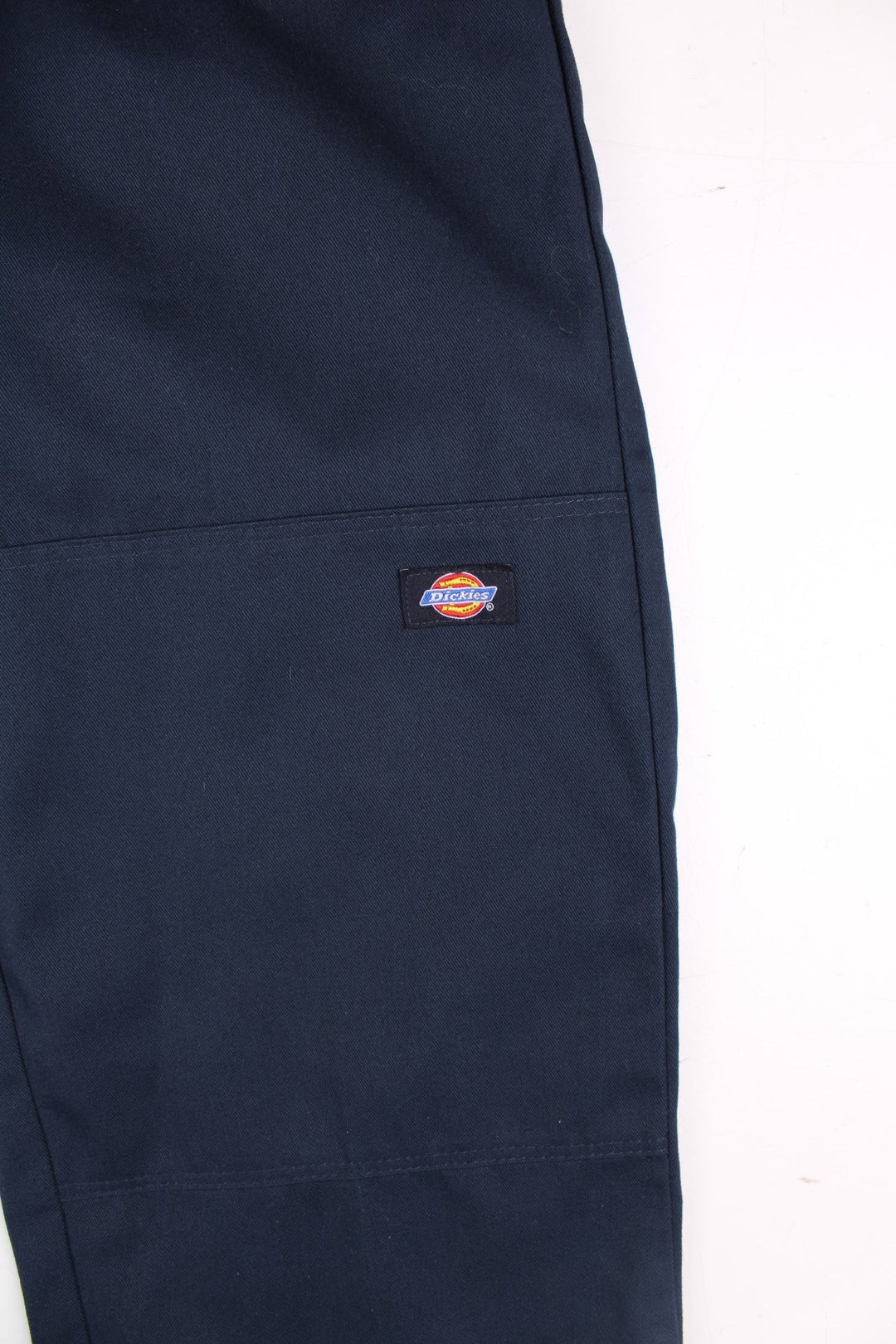 Dickies double-knee work trousers in navy blue with multiple pockets, zip and button closure, and a logo patch on the front.