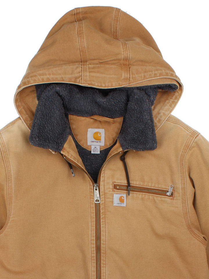 Carhartt Hooded Jacket in a brown colourway. Full zip with sherpa lining and multiple pockets on the front. Detachable hood, cuffed hem and sleeves, and has small classic logo on the front.