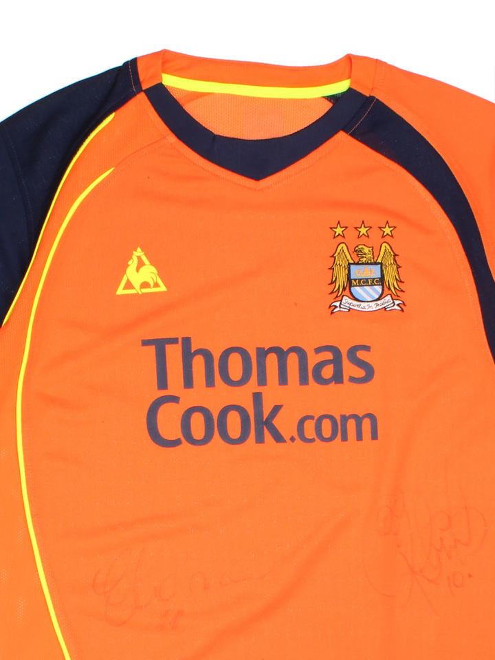 Manchester City 2008/09 Le Coq Sportif Football Shirt in the orange third kit colourway, features embroidered logo and badge on the front, and is signed by Elano number 11 and Robinho number 10.