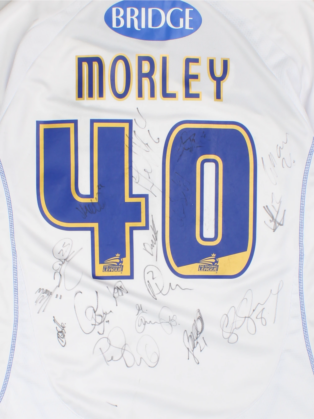 Vintage Bury FC 2012/13 Football Shirt in the white and blue home kit colourway, features embroidered logo and badge on the front, and on the back has Morley number 40 printed alongside team signatures.