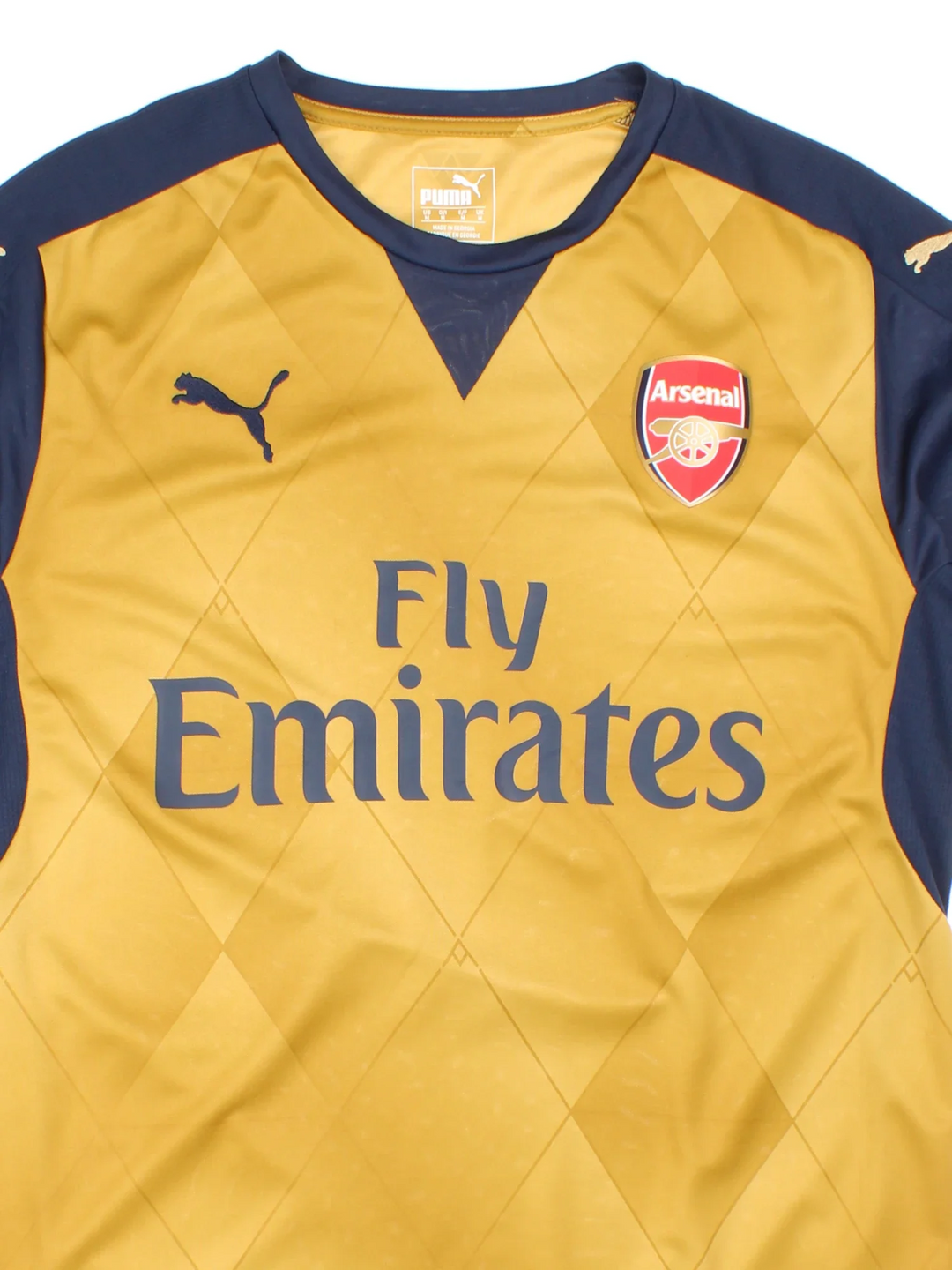 2015/16 Arsenal Puma Away Football Shirt in a golden brown and navy colourway with the logo and sponsor on the front.