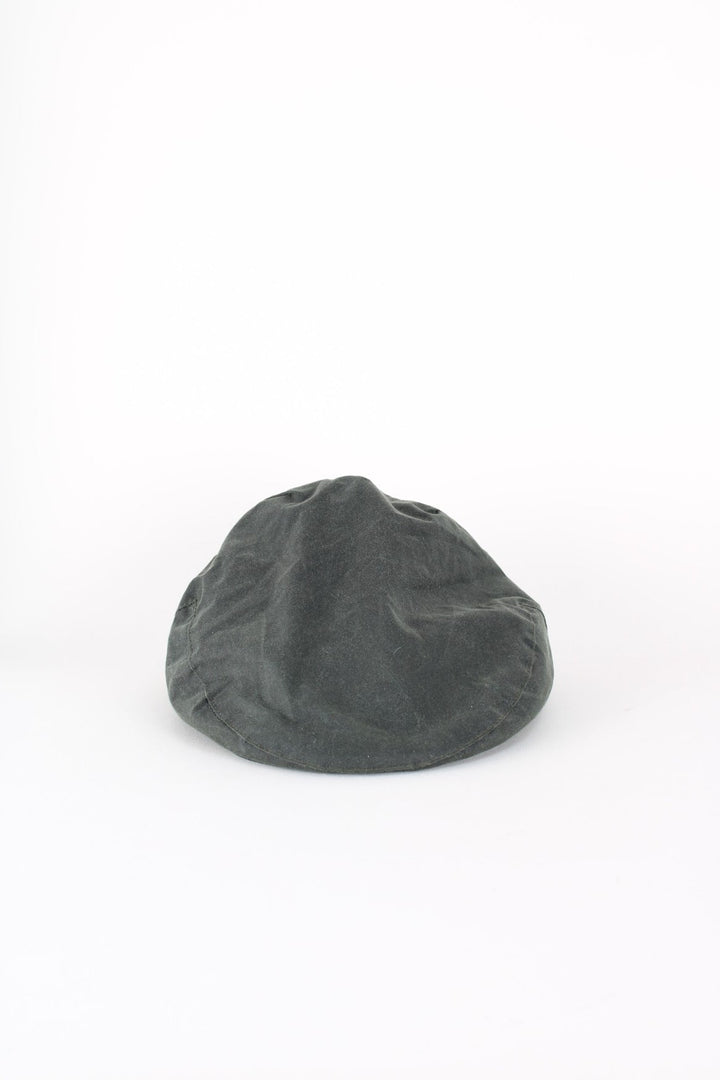 Vintage Barbour Wax Flat Cap in a dark green colourway with tartan lining, and has button closure at the top.