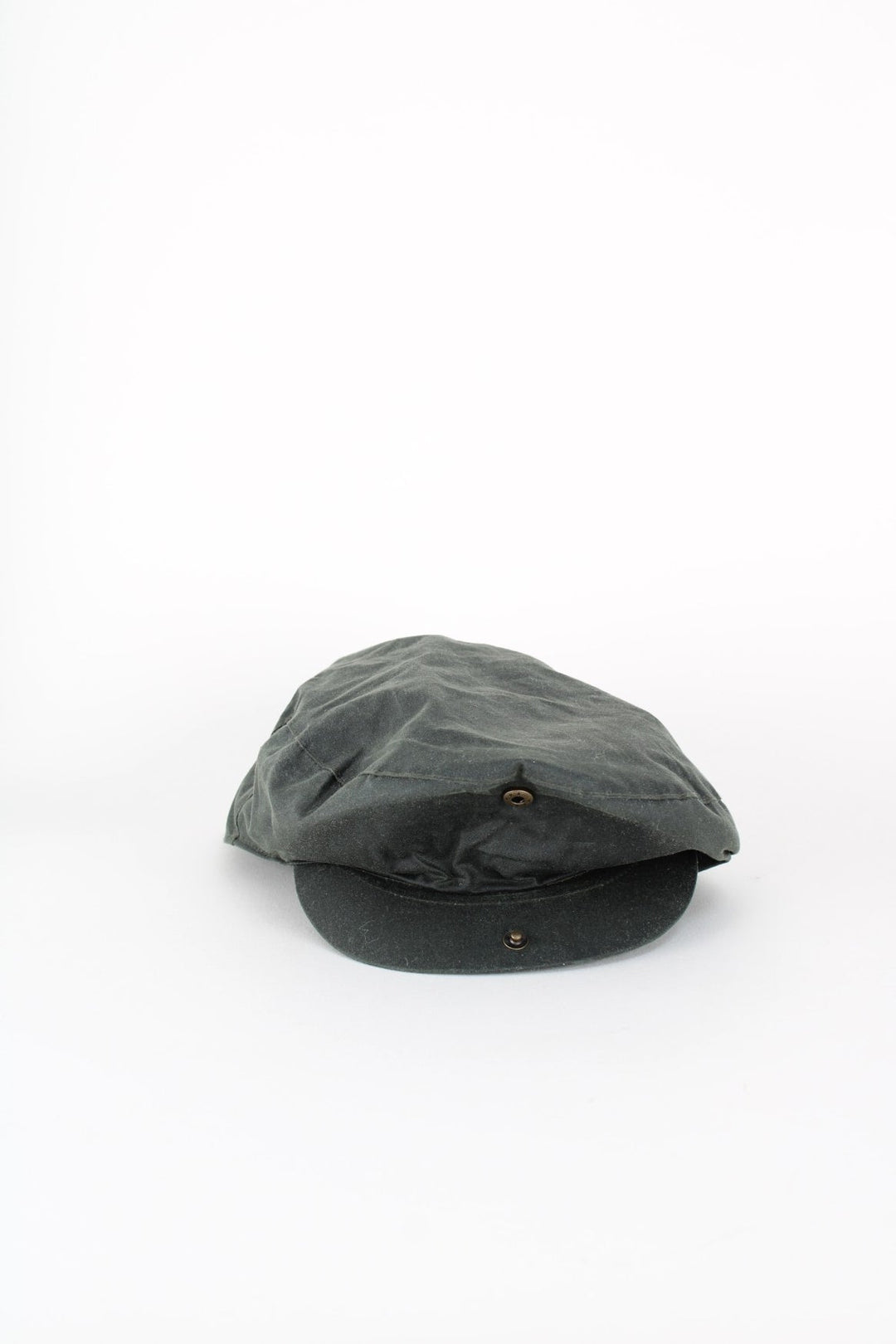 Vintage Barbour Wax Flat Cap in a dark green colourway with tartan lining, and has button closure at the top.