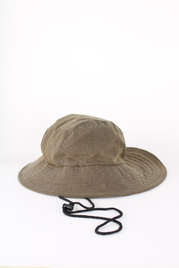 Barbour Wax Bucket Hat in a green colourway with tartan lining and ear flaps with drawstring..