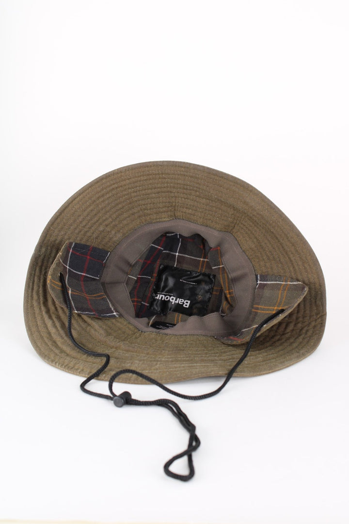 Barbour Wax Bucket Hat in a green colourway with tartan lining and ear flaps with drawstring..