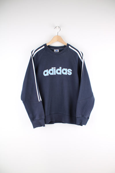 Adidas Sweatshirt in a blue colourway with three stripes going down sides, and has the logo spell out embroidered across the chest.