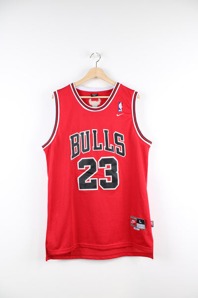 Chicago Bulls basketball jersey by Nike. Features embroidered Michael Jordan #23 lettering/ numbers on the front and back.  good condition- some creases in the 23 on the front/ back and discoloration to the white parts around the arm holes and inside of the neck (see photos)  Size in Label:  L - Length +2  Our Measurements:   Chest: 24 inches Length: 30 inches