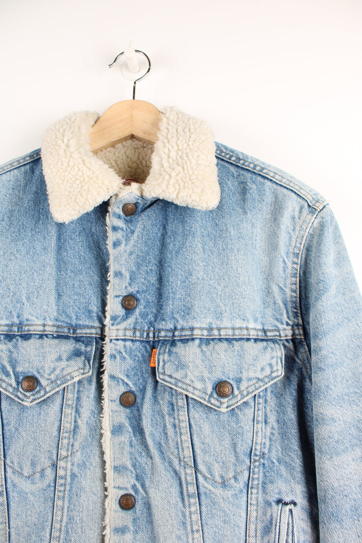 Vintage Levi's button up denim sherpa jacket in light blue with orange tab. Multiple pockets and white sherpa lining. 