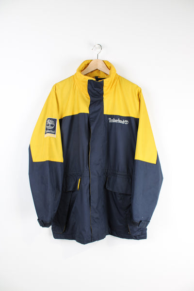 Timberland Performance blue and yellow zip through, waterproof jacket with multiple pockets and embroidered logo on the sleeve and chest