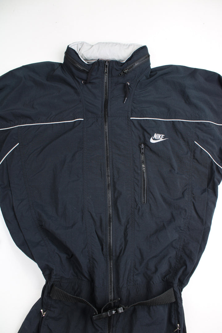 Vintage 90's Nike  black jumpsuit. Features embroidered logo on the chest, fold away hood and the waistband is elasticated at the back.  good condition - Four very small holes on the shoulder Size in Label: Mens M