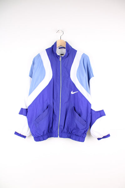 Nike Tracksuit Jacket in a blue and white patterned colourway, zip up with side pockets, and has the swoosh logo embroidered on the front and back.