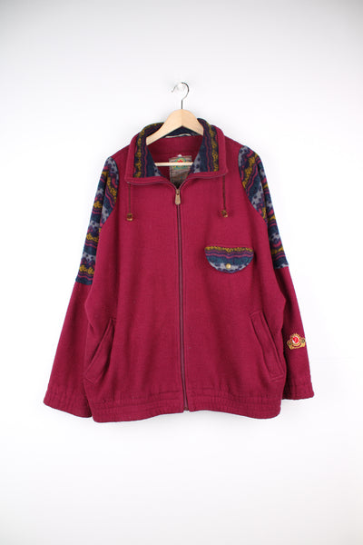 Fjallraven Original Fleece in a burgundy colourway with patterned patches on the shoulders and chest, zip up with multiple pockets, adjustable collar, and has the logo embroidered on the left sleeve.