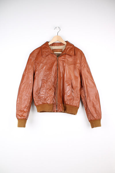 Vintage orange/deep tan leather bomber jacket by William Barry with western style yoke on the front and back and faux shearling lining 