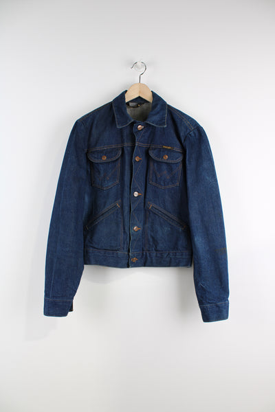 Vintage Wrangler Denim Jacket in a blue colourway with brown cross stitching, button up, multiple pockets, and has logo embroidered on the chest.