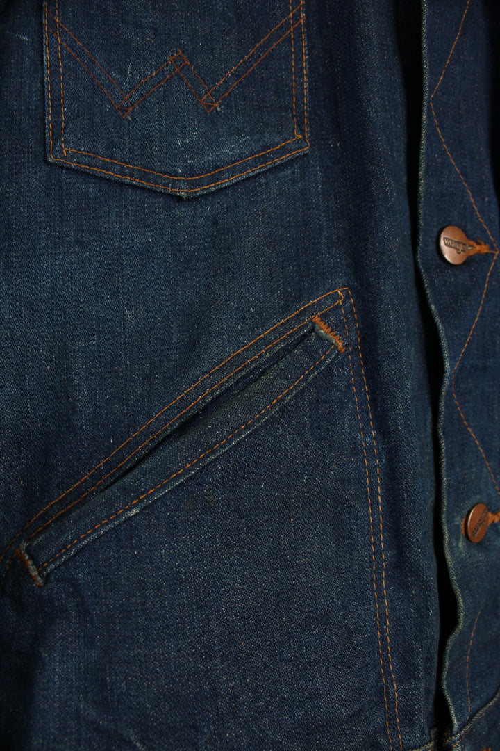 Vintage Wrangler Denim Jacket in a blue colourway with brown cross stitching, button up, multiple pockets, and has logo embroidered on the chest.