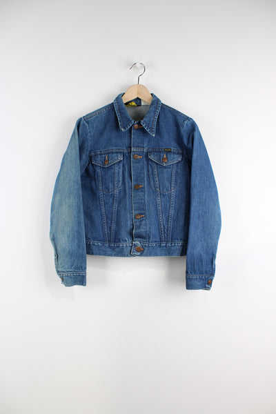 Vintage Wrangler Denim Jacket in a blue colourway, button up, double chest pockets, and has logo embroidered on the chest.