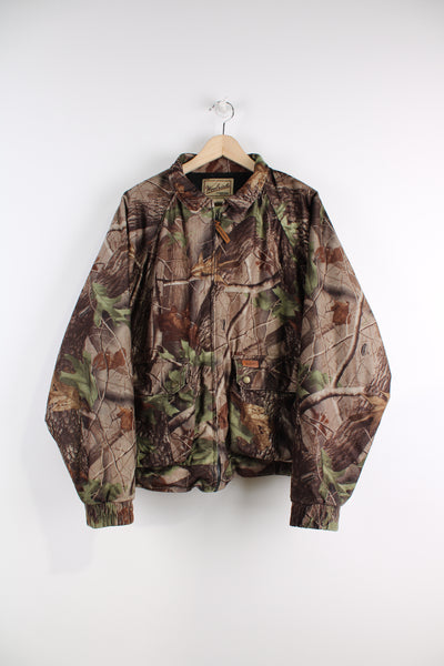 Woolrich Real Tree Camo Bomber Jacket, hunting style, zip up, multiple pockets, and has logo embroidered on the front.