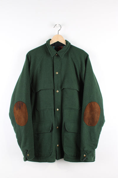 Vintage Woolrich wool chore jacket in green, button up with multiple pockets, tartan lining and brown elbow pads.